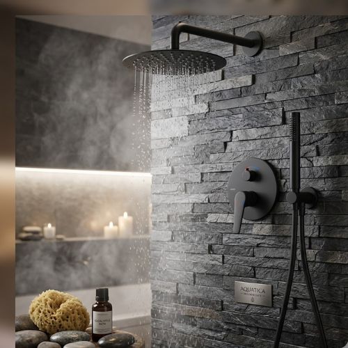 Matte black concealed rainfall shower active on a dark slate wall, featuring a circular mixer, slim handheld wand, and spa accessories with soft candlelight.
