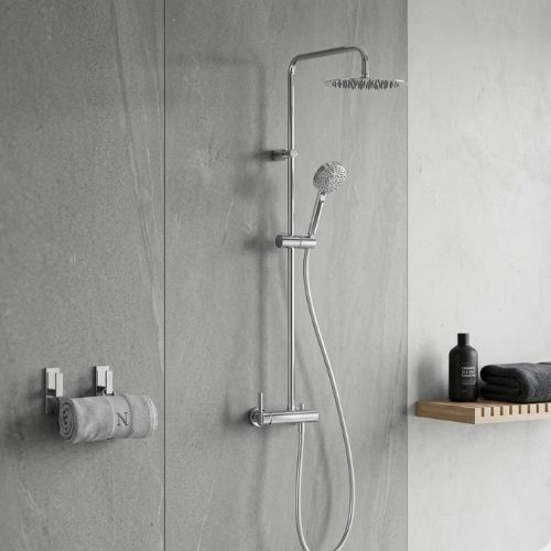 Chrome rainfall shower system on a grey stone wall with a Neatflow towel and spa accessories.