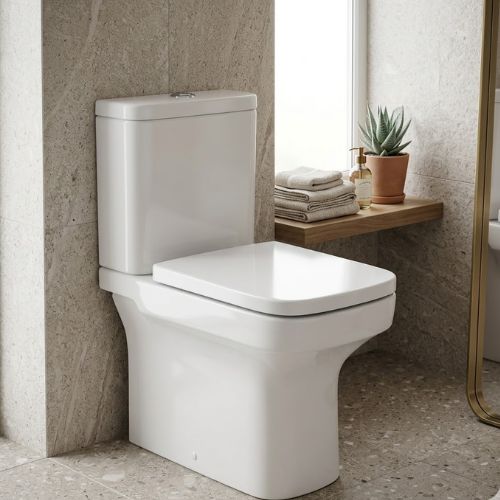 Floor-standing ceramic WC with a fully skirted back-to-wall base and Alpine White gloss finish, positioned against a decorative stone-tiled wall in a spa-style setting.