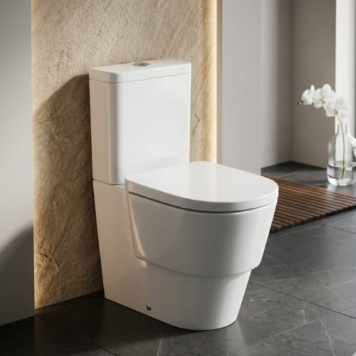 Sleek Tura WC in brilliant white ceramic, featuring a modern skirted design in a luxury bathroom with marble floors and warm accent lighting.
