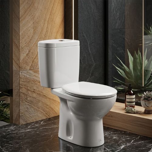 Classic Victoria WC in brilliant white ceramic, featuring a traditional silhouette and soft-close seat, set in a luxury bathroom with dark marble floors and warm stone-textured walls.