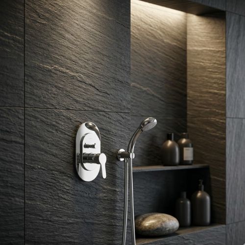 Modern chrome concealed shower mixer valve and handheld showerhead set mounted on a dark chiseled slate wall with warm accent lighting.