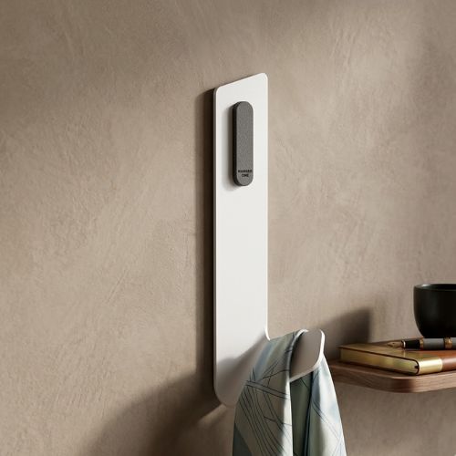 A sleek, white minimalist wall hook featuring a charcoal gray accent, mounted on a textured beige wall in a modern, sophisticated interior.