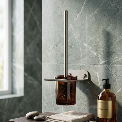 Modern wall-mounted toilet brush holder with an amber glass container and brushed metal hardware, set against a luxurious green marble bathroom wall.