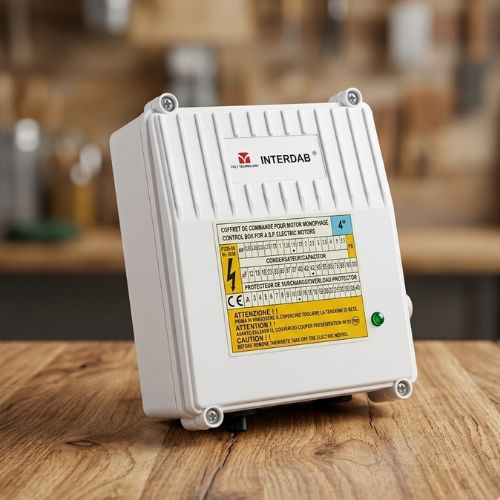 A brand-new Interdab 1.5HP single-phase water pump control box with technical yellow specifications label, neatly displayed on a rustic wooden tabletop studio setup.