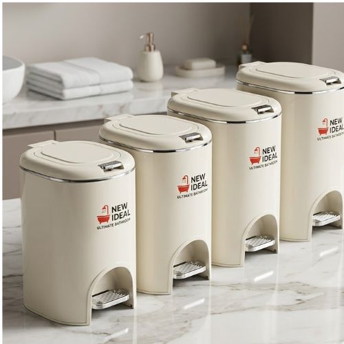 A set of four elegant cream-colored, foot-operated pedal waste bins in varying sizes, arranged on a marble surface.