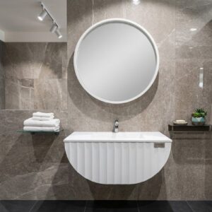 A sleek, modern wall-mounted bathroom vanity with a fluted white finish and a circular mirror in a luxurious, tiled bathroom setting.