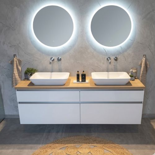 A modern, minimalist floating double vanity featuring white cabinetry, a light wood countertop with dual vessel sinks, and twin circular LED-lit mirrors, set against a grey textured wall with a round jute rug in the foreground.
