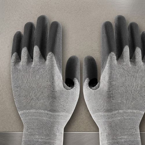 A pair of Athletic D5 XP industrial cut-resistant gloves with black-coated fingers and palms and a gray knit back, displayed against a metallic industrial background.