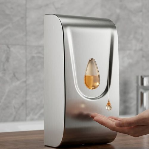 A sleek, silver stainless steel wall-mounted soap and sanitizer dispenser with a visible liquid level, positioned on a modern wood-textured surface with a bathroom faucet in the background.