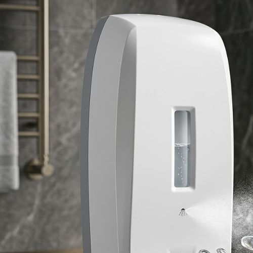 A sleek, white wall-mounted automatic spray dispenser shown in a modern bathroom, featuring a transparent window and a glowing sensor light.