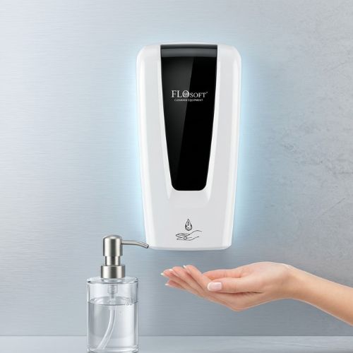 An automatic touchless liquid soap dispenser mounted on a wall with a hand placed underneath to receive soap.