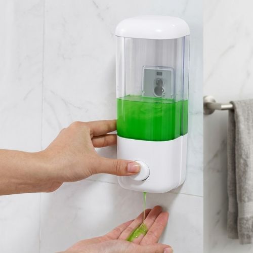 A 500ml manual wall-mounted soap dispenser being used to dispense liquid soap into a person's hand.